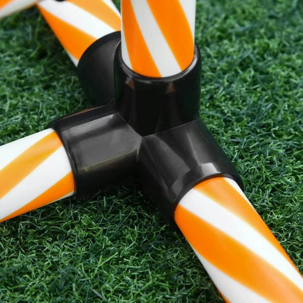Close-up of orange and white weave pole with black base on grass