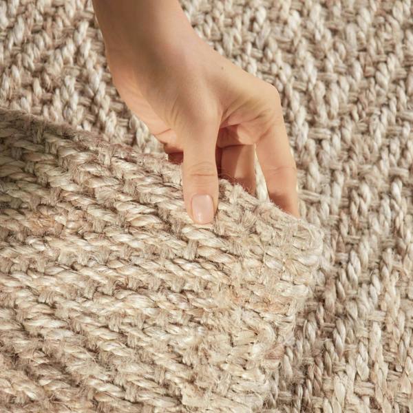 Hand touching a textured beige carpet
