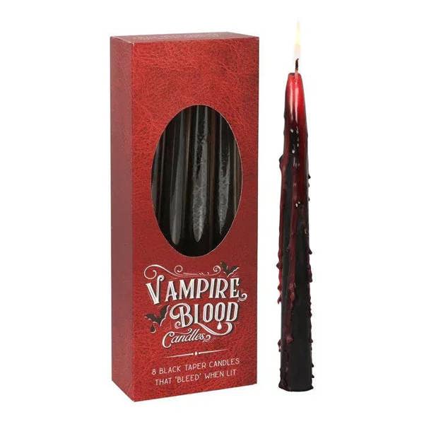 Red candle box with oval window and one black taper candle with red wax tip