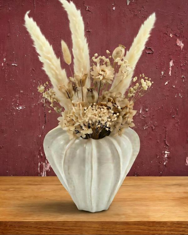 Decorative vase with dried plants against a textured red wall