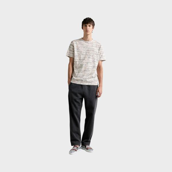 Supplied Fashion model wearing a Missoni space-dyed multi-coloured cotton short-sleeve t-shirt with dark trousers.