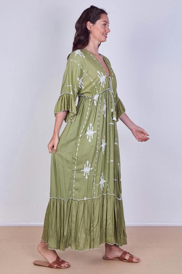 Woman wearing a green dress with white patterns on a plain background