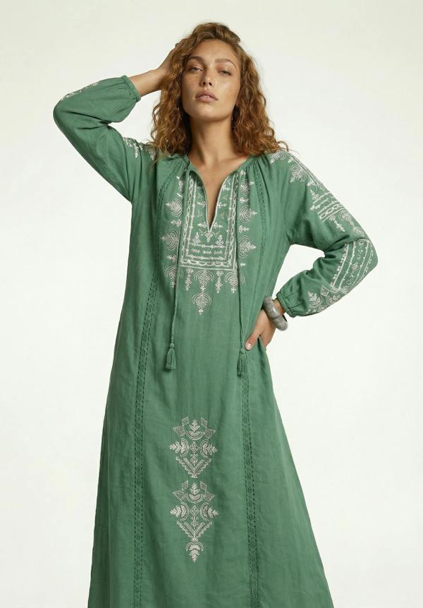Woman wearing a green embroidered dress on a white background