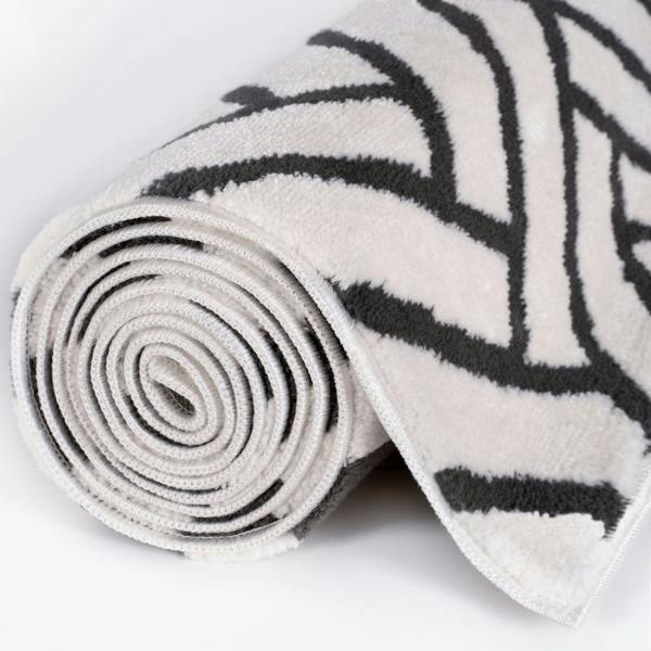 Rolled-up rug with black geometric pattern on a white background