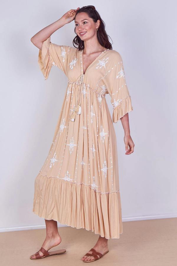 Woman wearing a beige dress with floral patterns against a white background