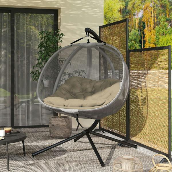 Outdoor double hanging egg chair with grey mesh pod and beige cushion on black stand.