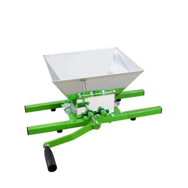 KuKoo fruit crusher featuring a stainless steel hopper, green metal frame, and a hand crank for easy fruit processing