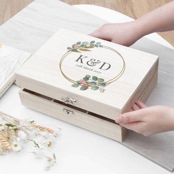 A hands-on view of the personalised wooden wedding memory box by Abode Home & Gifts featuring a botanical printed lid.