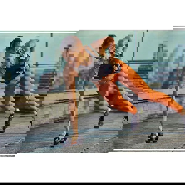 Woman exercising with 3kg dumbbells on a rooftop with cityscape background