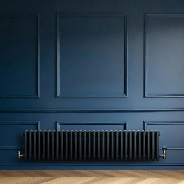 Traditional anthracite 4 column radiator against a deep blue wall, featuring a sleek, curved design and a textured finish