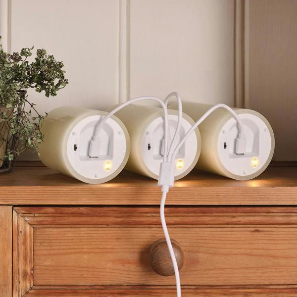 TruGlow ivory rechargeable LED candles on a wooden surface showing the USB charging cables and indicator lights.