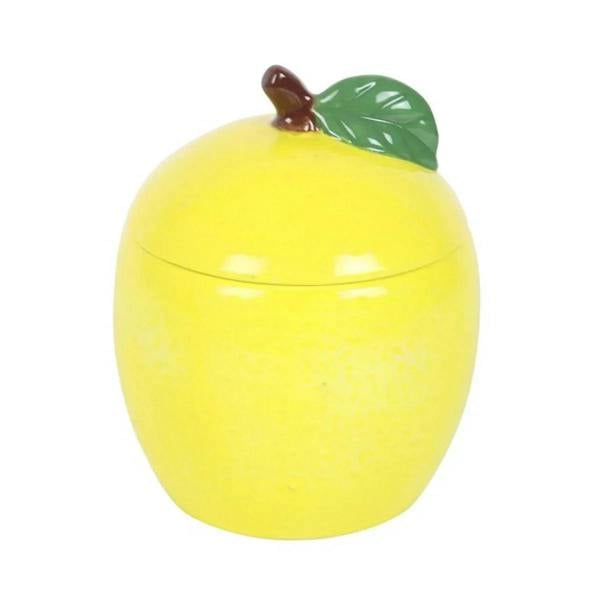 Yellow lemon-shaped candle jar with leaf-shaped lid and wick, glossy ceramic close-up.