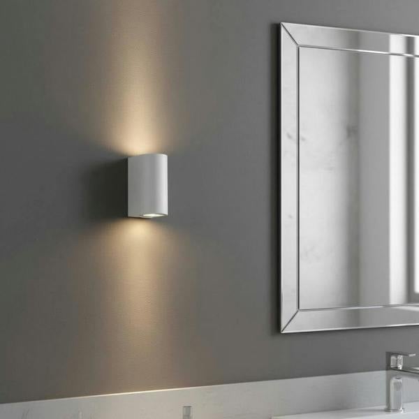 white contemporary sconce for bathroom mounted next to a bathroom mirror 