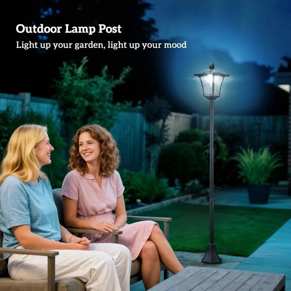 Black outdoor garden post lantern, lit, standing along walkway