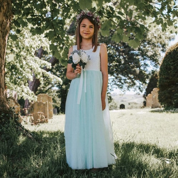 Young girl in a light blue dress holding flowers in a cemetery