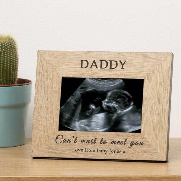 A personalised oak baby scan picture frame by Abode Home & Gifts displaying a black and white ultrasound photo.