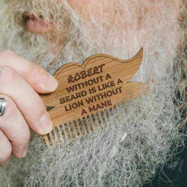 Personalised walnut wooden beard comb shaped like a moustache engraved with Robert without a beard is like a lion without a mane being used on a gray beard