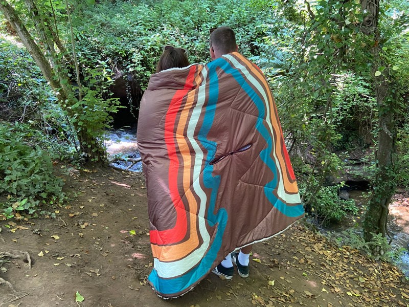 A young couple, huddled together with a vivid spruce outdoor sherpa fleece lined Blanko blanket outdoors. imageset:Vivid Spruce