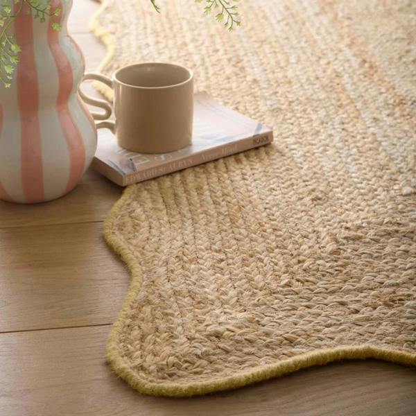 Natural woven rug on a wooden floor with a cup and vase.