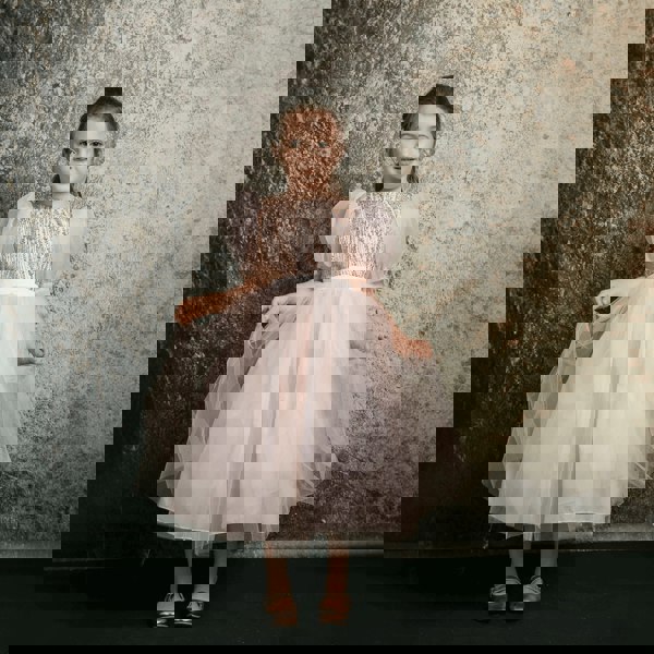 Dark haired girl wearing a blush coloured party dress from UK Flower Girl Boutique