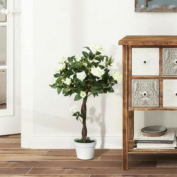 Artificial white rose floral plant in white pot with green leaves and brown trunk