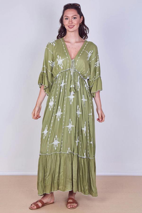 Woman wearing a green dress with white patterns on a plain background