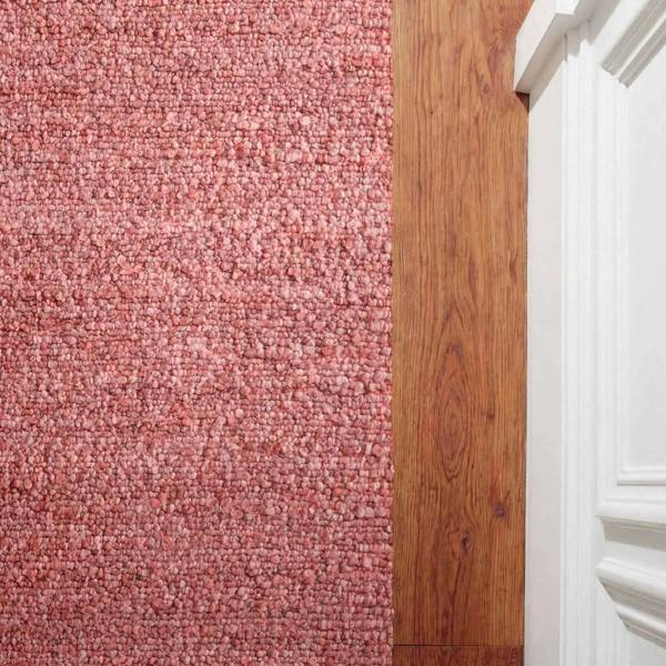 Transition from pink carpet to wooden floor with white baseboard.