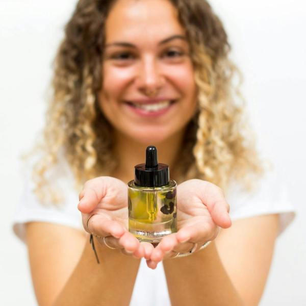 Woman holding Into the Wild Daily Aromatherapy Mood Oil glass bottle out in both hands towards the camera by Abode Home & Gifts