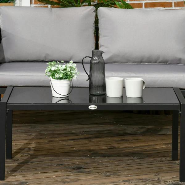 Black-framed tempered glass coffee table with potted decor between light grey patio cushions