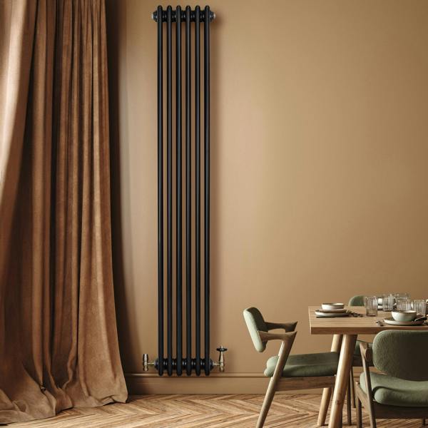 Traditional black 4 column radiator, 1800 x 290mm, mounted on a warm-toned wall, complementing a stylish dining area with wooden flooring