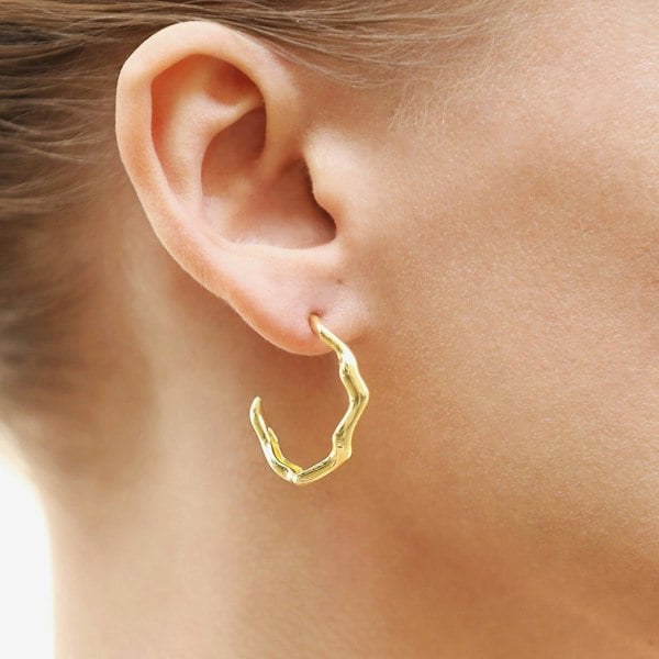 An ear with wavy hoop earring.