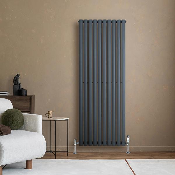 Anthracite grey oval single column radiator with vertical bars, mounted on a textured wall, complementing modern interior decor