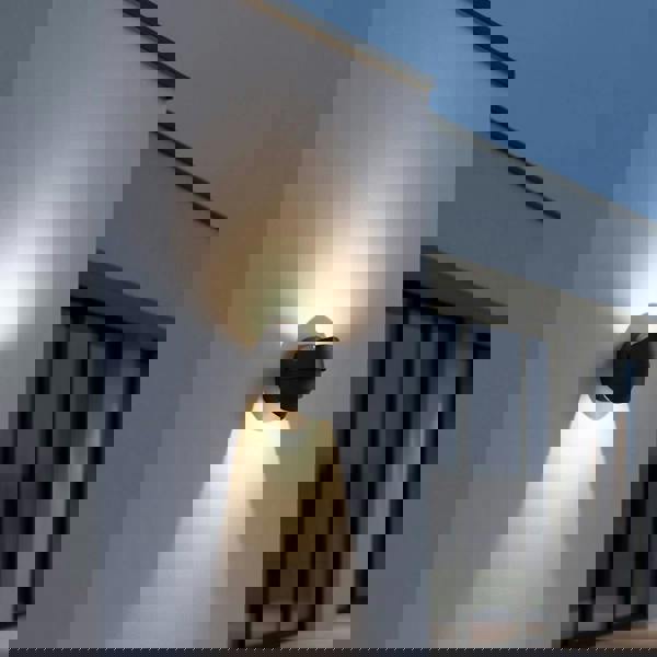 black modern outdoor wall lamp mounted on a white wall outside of a modern house