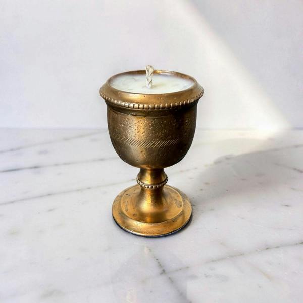 Brass candle holder with a candle on a marble surface