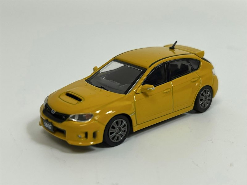 a yellow toy car on a white surface
