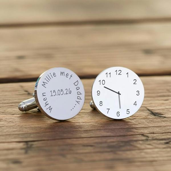 A pair of round rhodium-plated cufflinks on a rustic wooden background, one engraved with a birth clock face and the other etched with 'When Millie met Daddy' and a date.