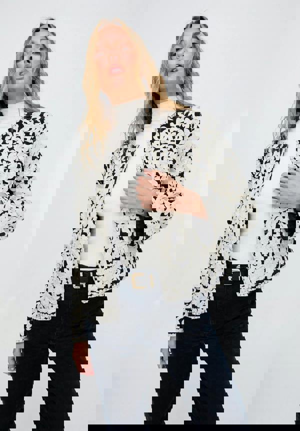 Woman wearing a black and white patterned jacket on a plain background