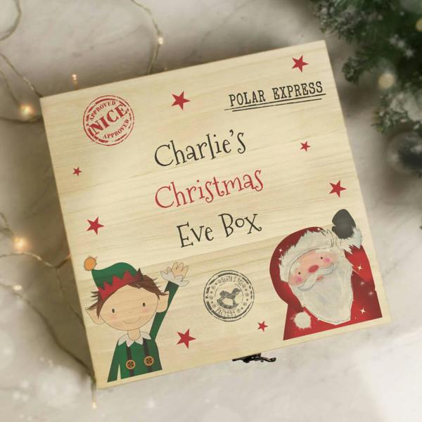 Personalised wooden Christmas Eve box featuring illustrations of Santa Claus, a waving Christmas elf, stars, and custom name text.