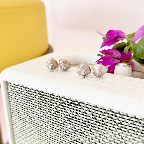 Silver heart pearl earrings showcased on an Artdeco radio.
