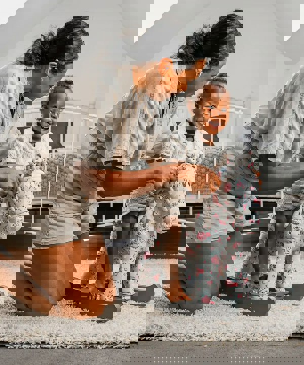 little girl and mum playing with floral baby rocker 