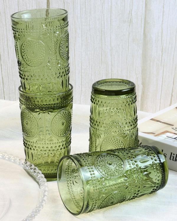 Set of green patterned glass tumblers on a light surface with a white textured background