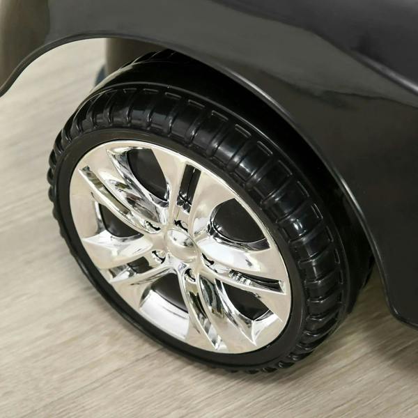Close-up of black ride-on car front wheel with chrome spokes and textured tire