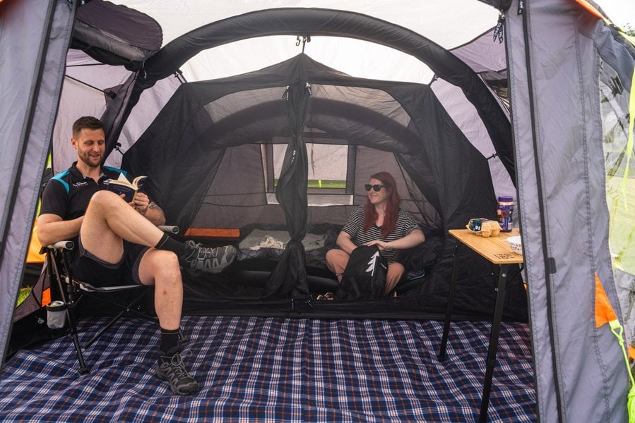 A male and female inside of the Abberley Xl Breeze® 4 Berth Inflatable Tent from OLPRO showing the inner bedroom with sleeping bags stowed inside of them.