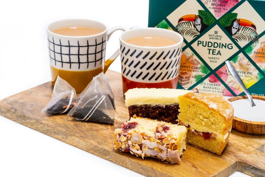 Two Mugs of Natural & Noble Pudding Tea, Alongside Victoria Sponge and Carrot Cake.