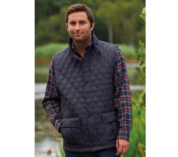 Countryman Wearing Champion Ashby Quilted Gilet in Navy next to a lake