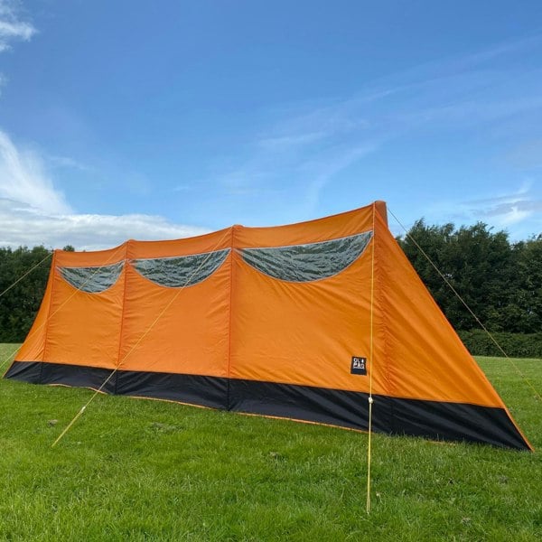 The OLPRO Inflatable Orange Windbreak pitched in a field with blue sky.