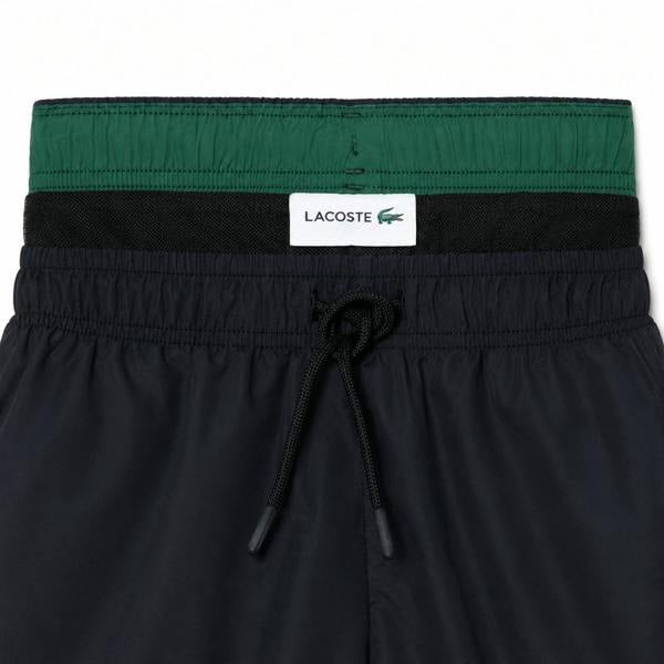 Lacoste black quick-dry swim shorts with a green waistband and drawstring.