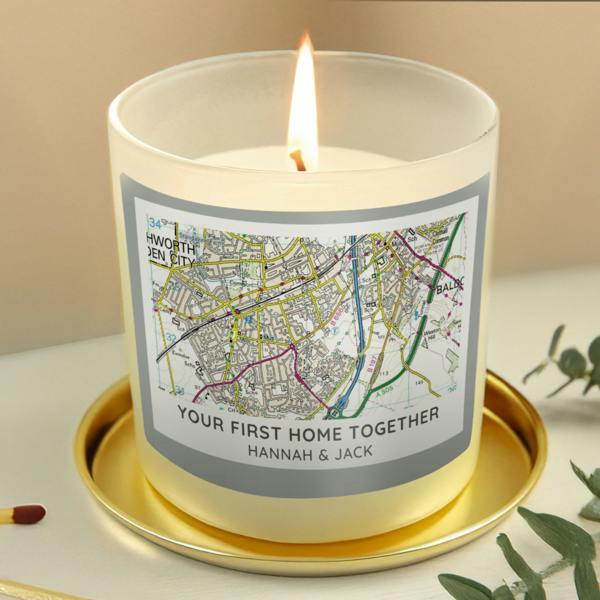 A personalised new home map candle with a label reading Your First Home Together Hannah and Jack on a gold coaster.