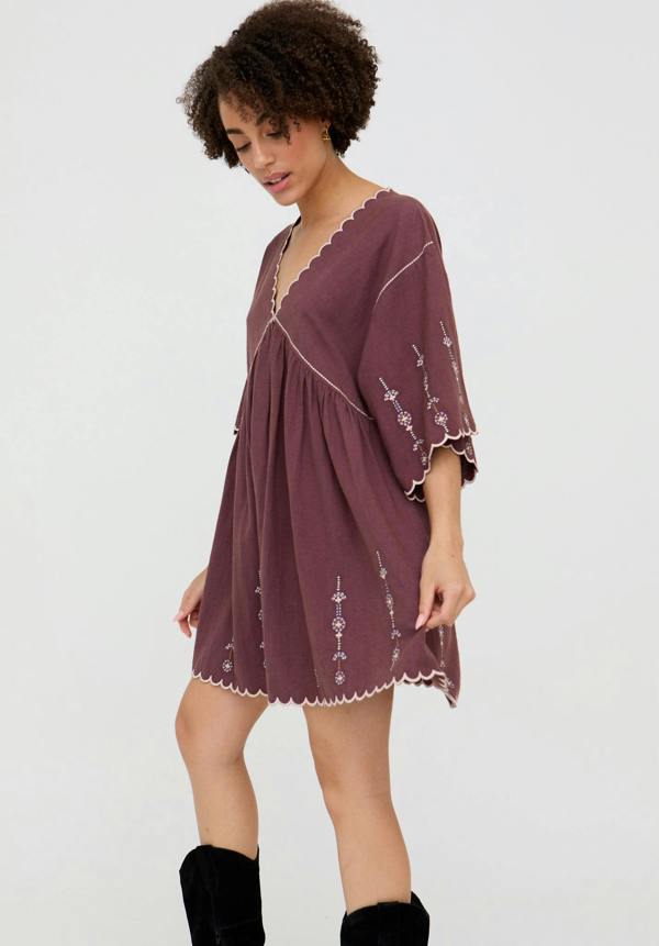 Woman wearing a burgundy dress with lace trim on a white background
