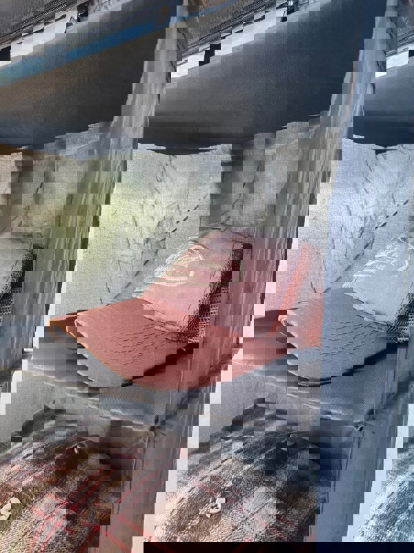 A close up of a Camping Organiser with Shelves and Storage Bag by OLPRO hanging in a campervan awning with a cap on the shelf.